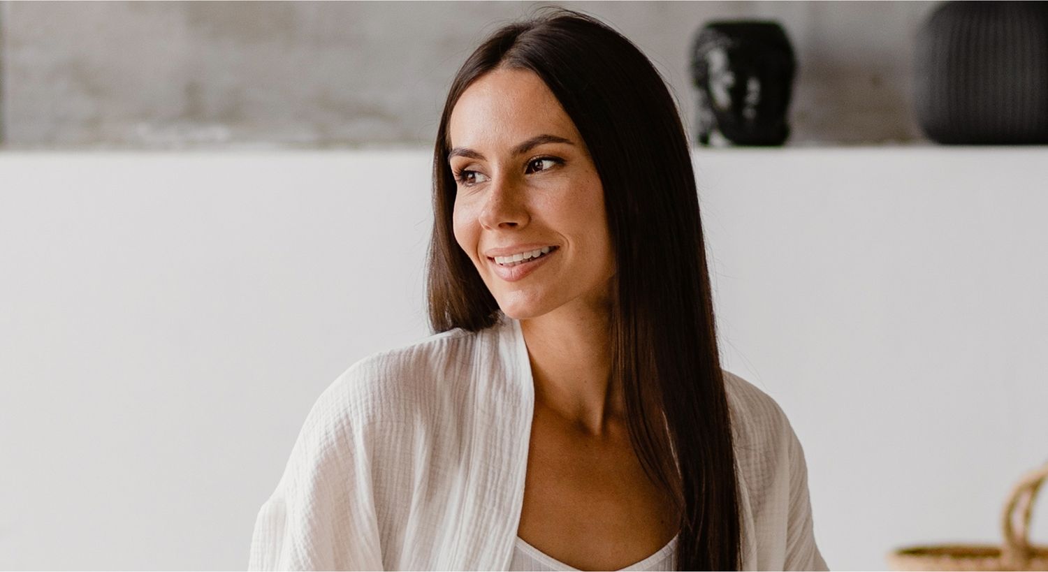 Smiling woman in a minimalist indoor setting.