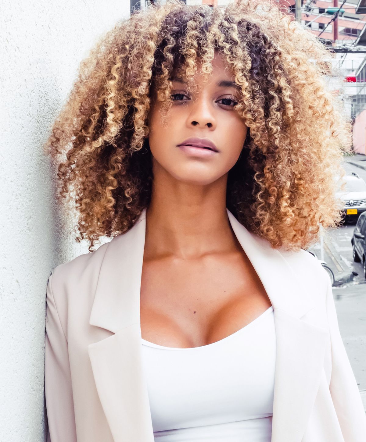 Woman with curly hair posing outdoors.