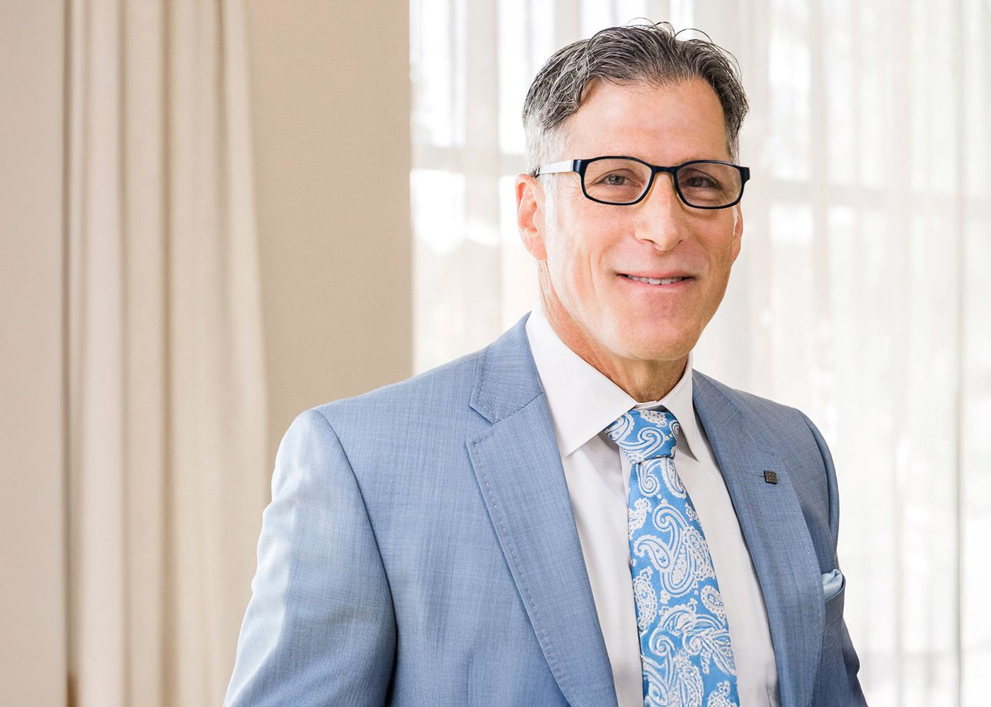 Man in a light suit smiling at the camera.