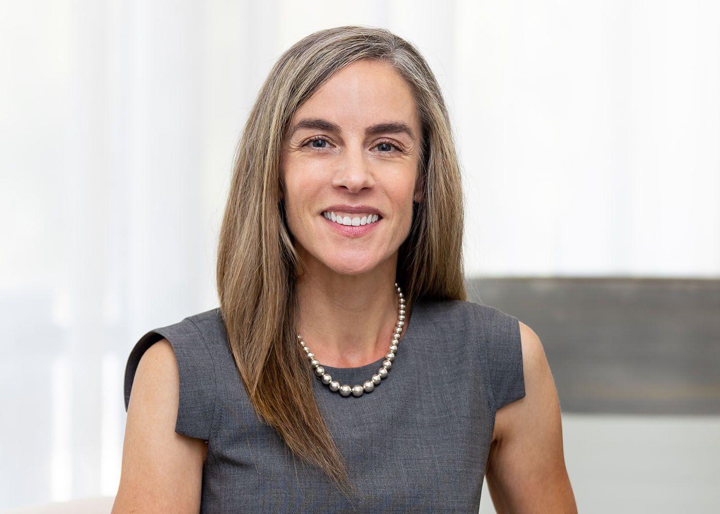 Smiling woman with long hair in black top.