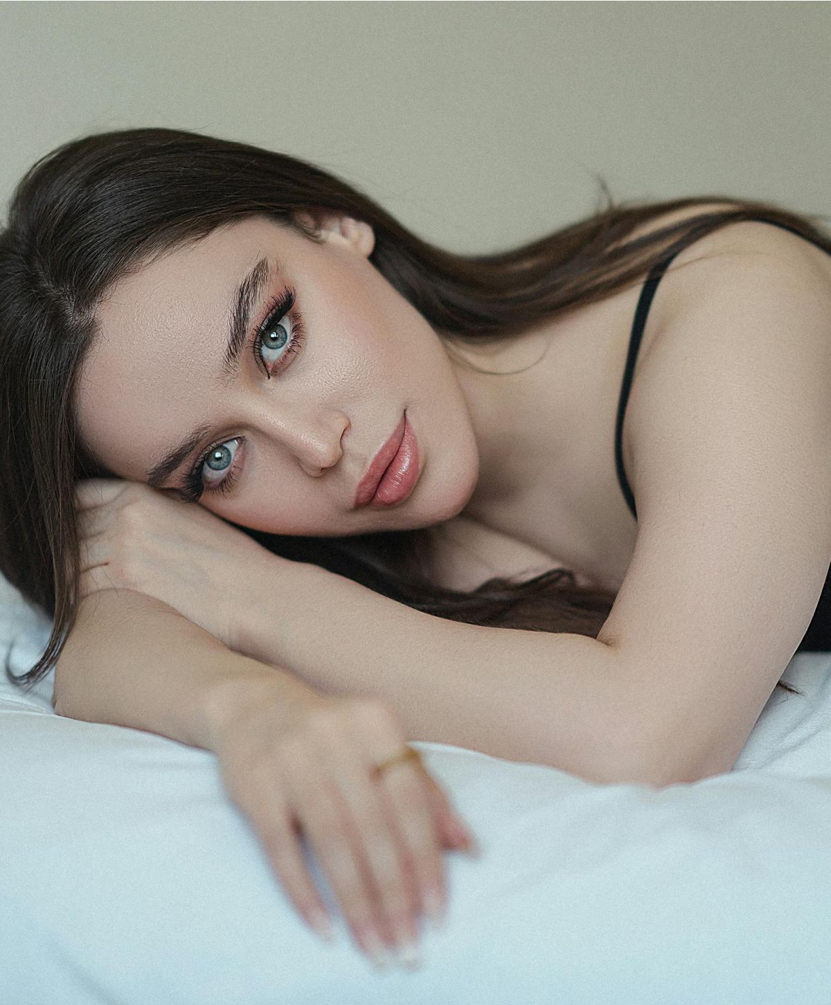 Woman resting on a bed with thoughtful expression.