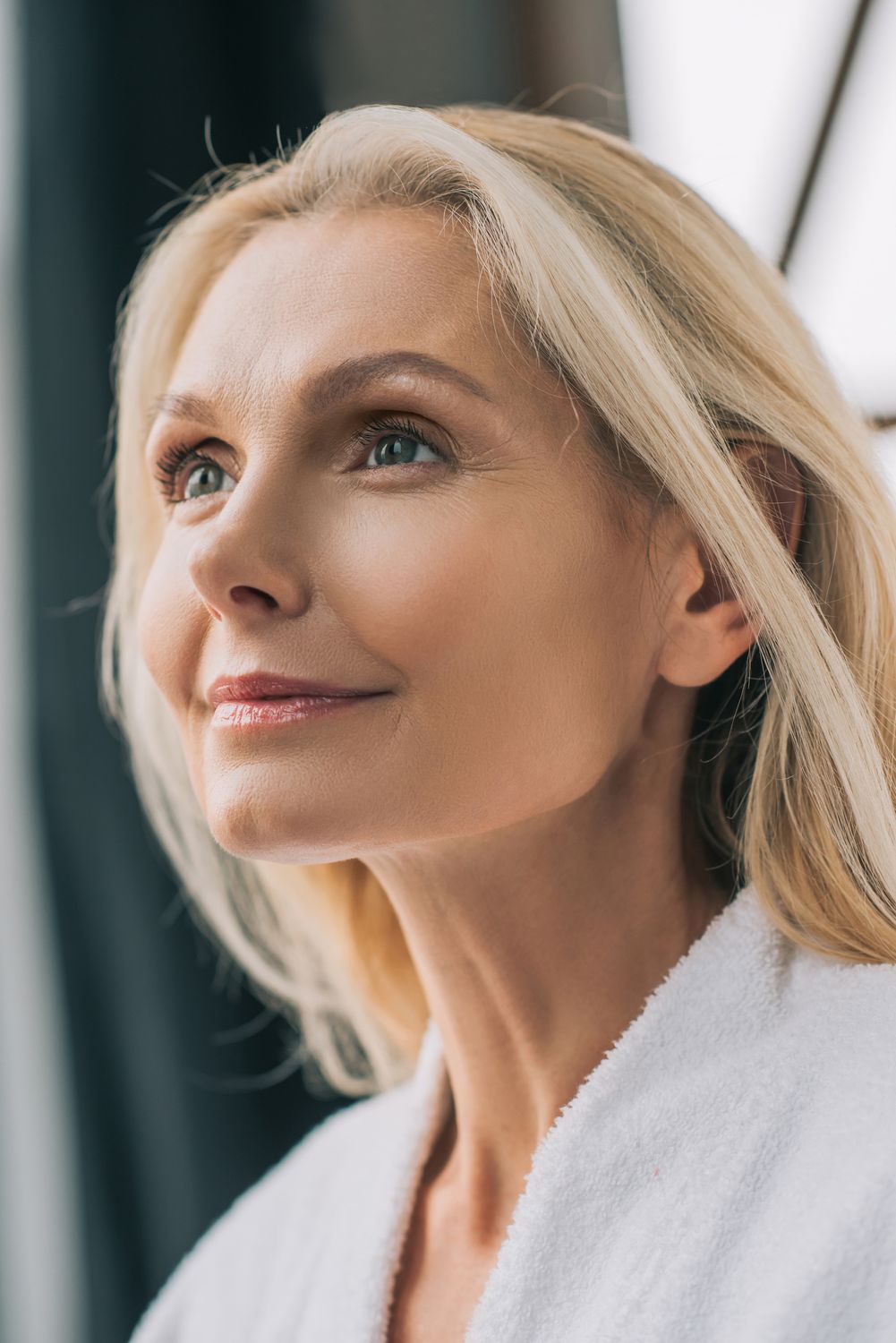 Woman in white blazer with elegant jewelry.