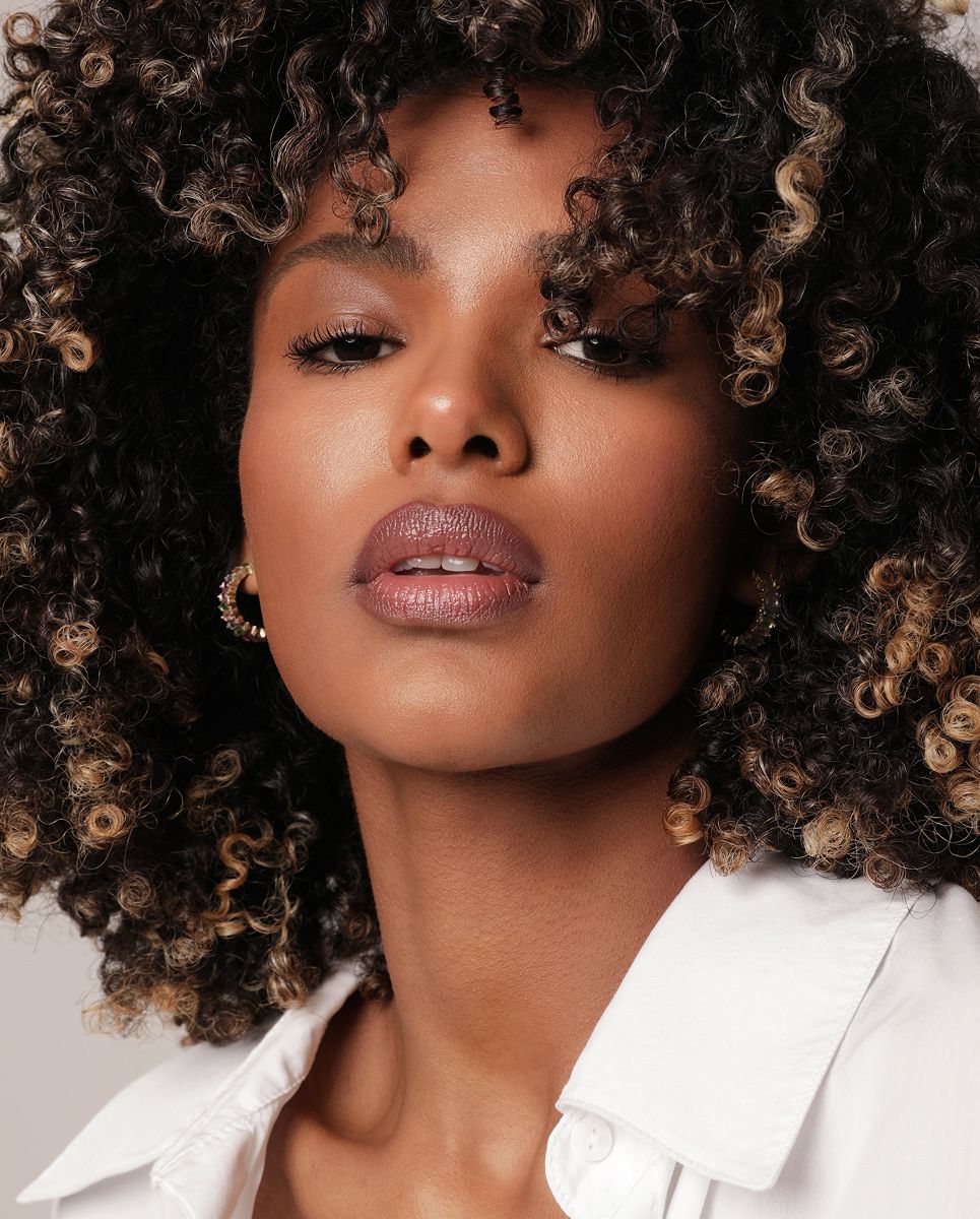Woman with curly hair and natural makeup.