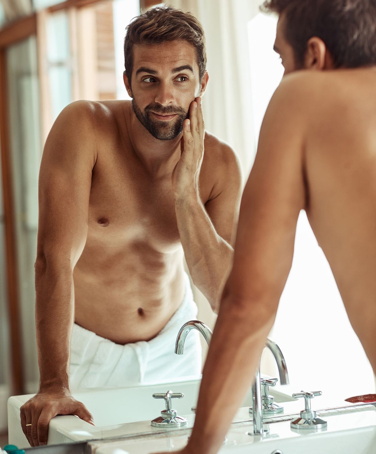 Man examining his reflection in bathroom mirror.