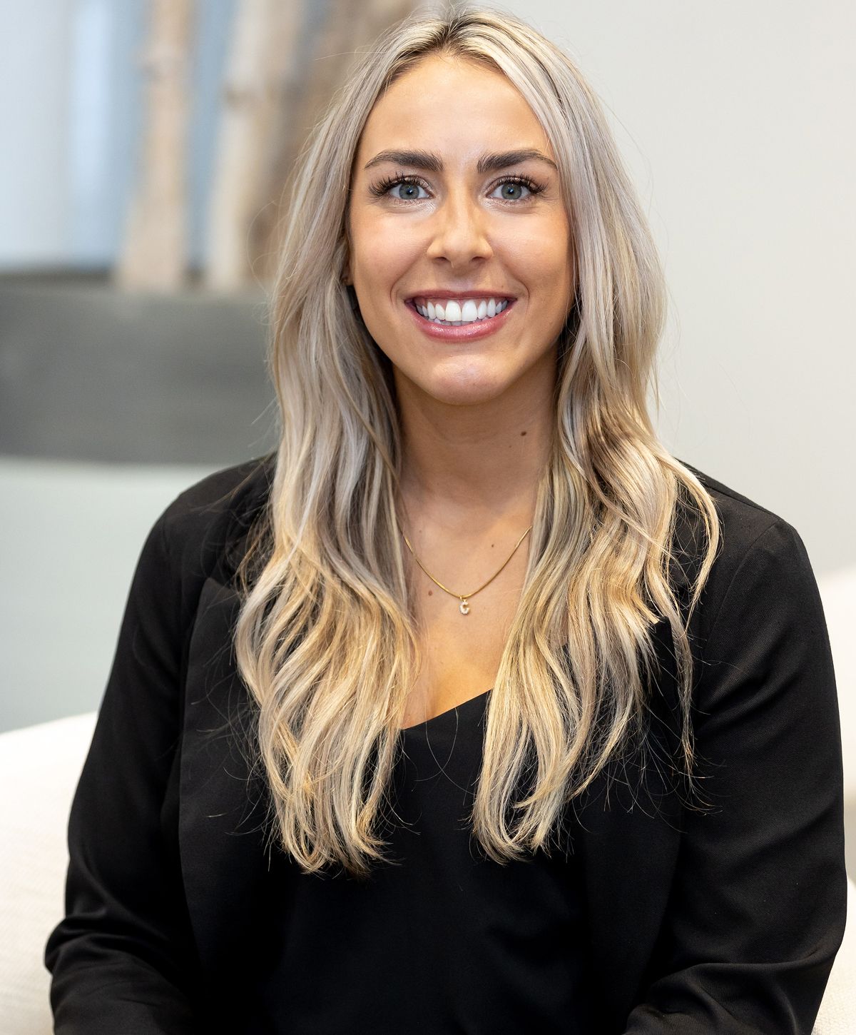 Smiling woman with long blonde hair in black outfit.