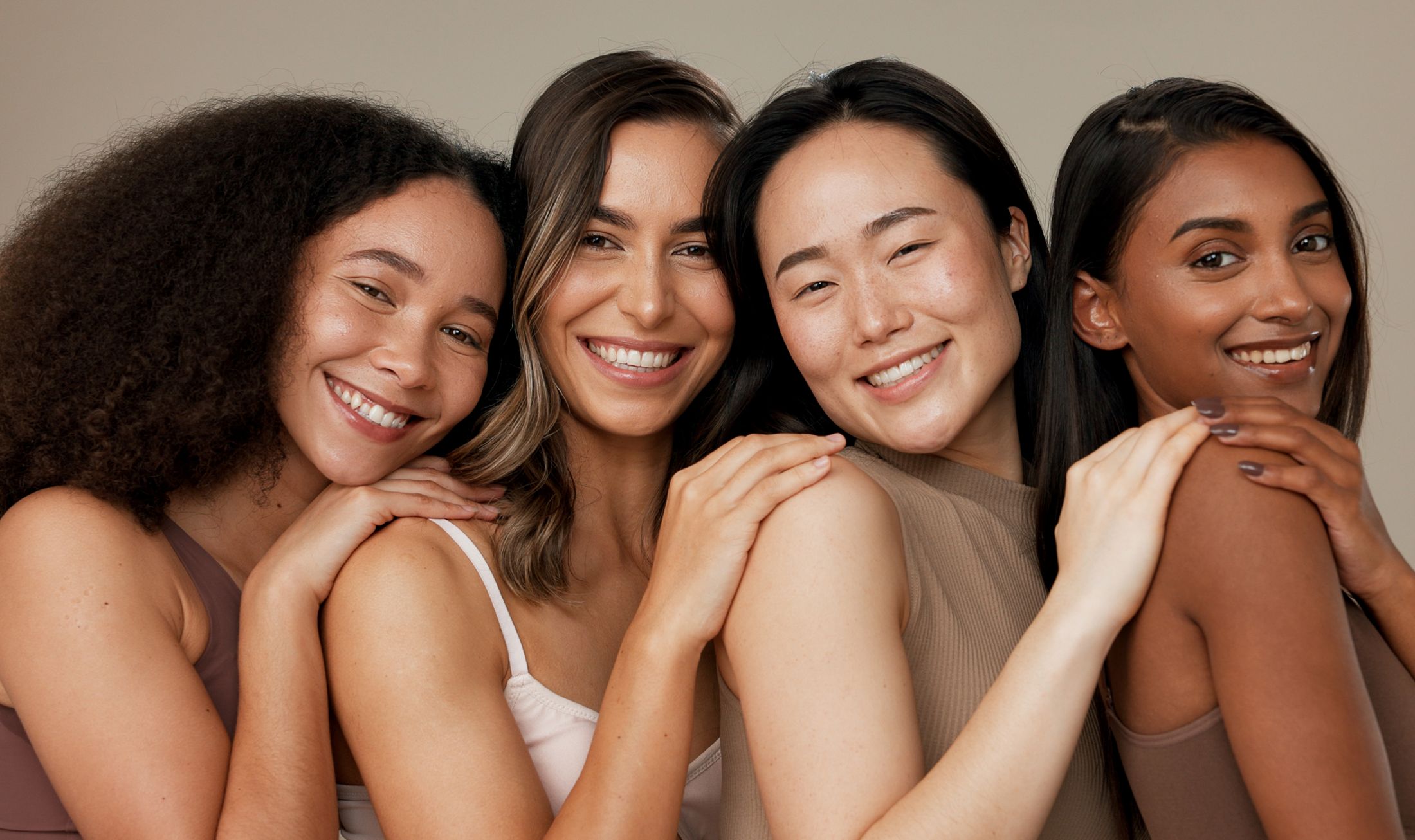 Diverse group of smiling women posing together.
