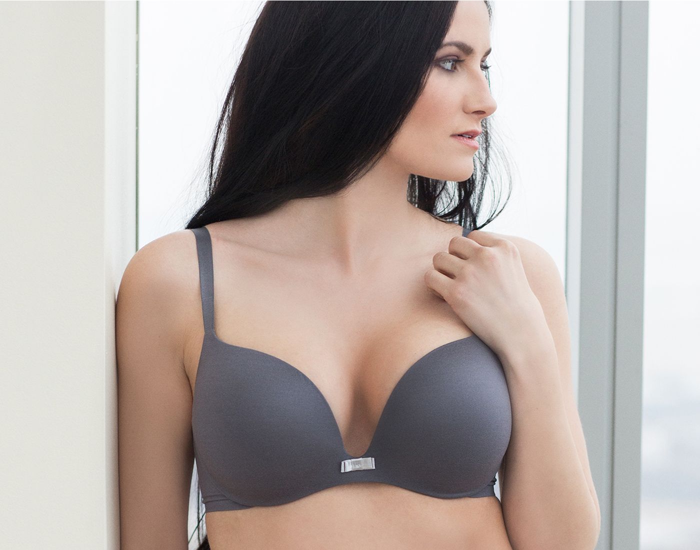 Model wearing a gray padded bra by window.
