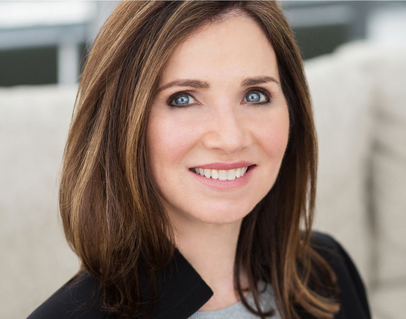 Smiling woman with long brown hair indoors.