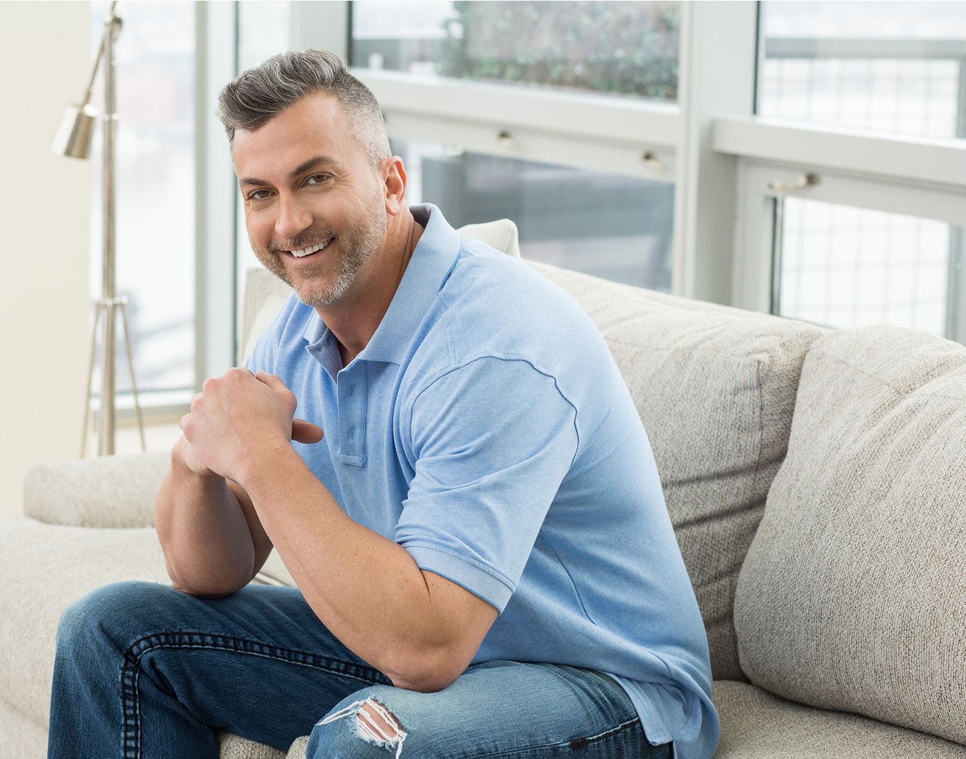 Smiling man sitting on a couch indoors.