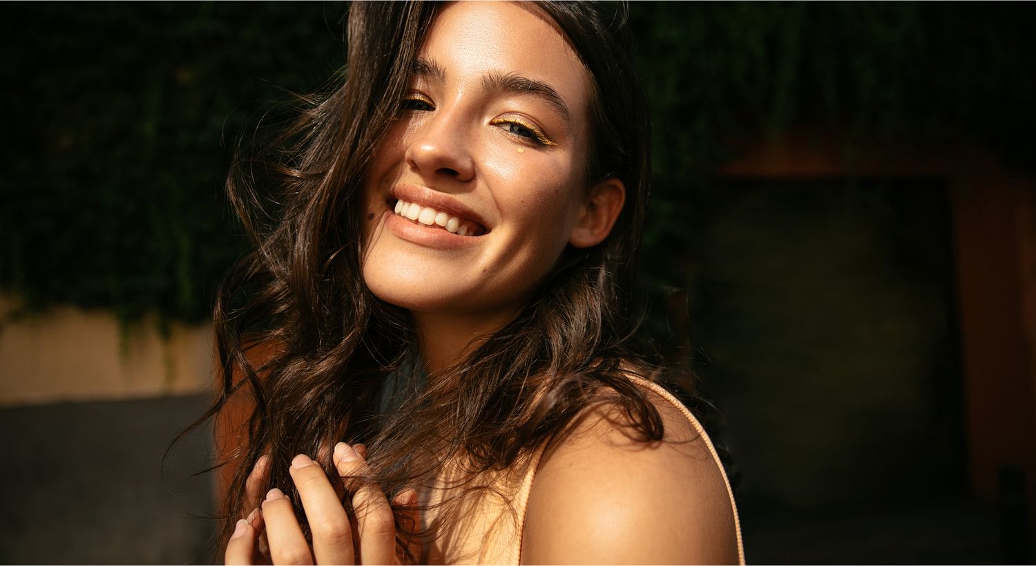 Smiling woman with long hair in sunlight.
