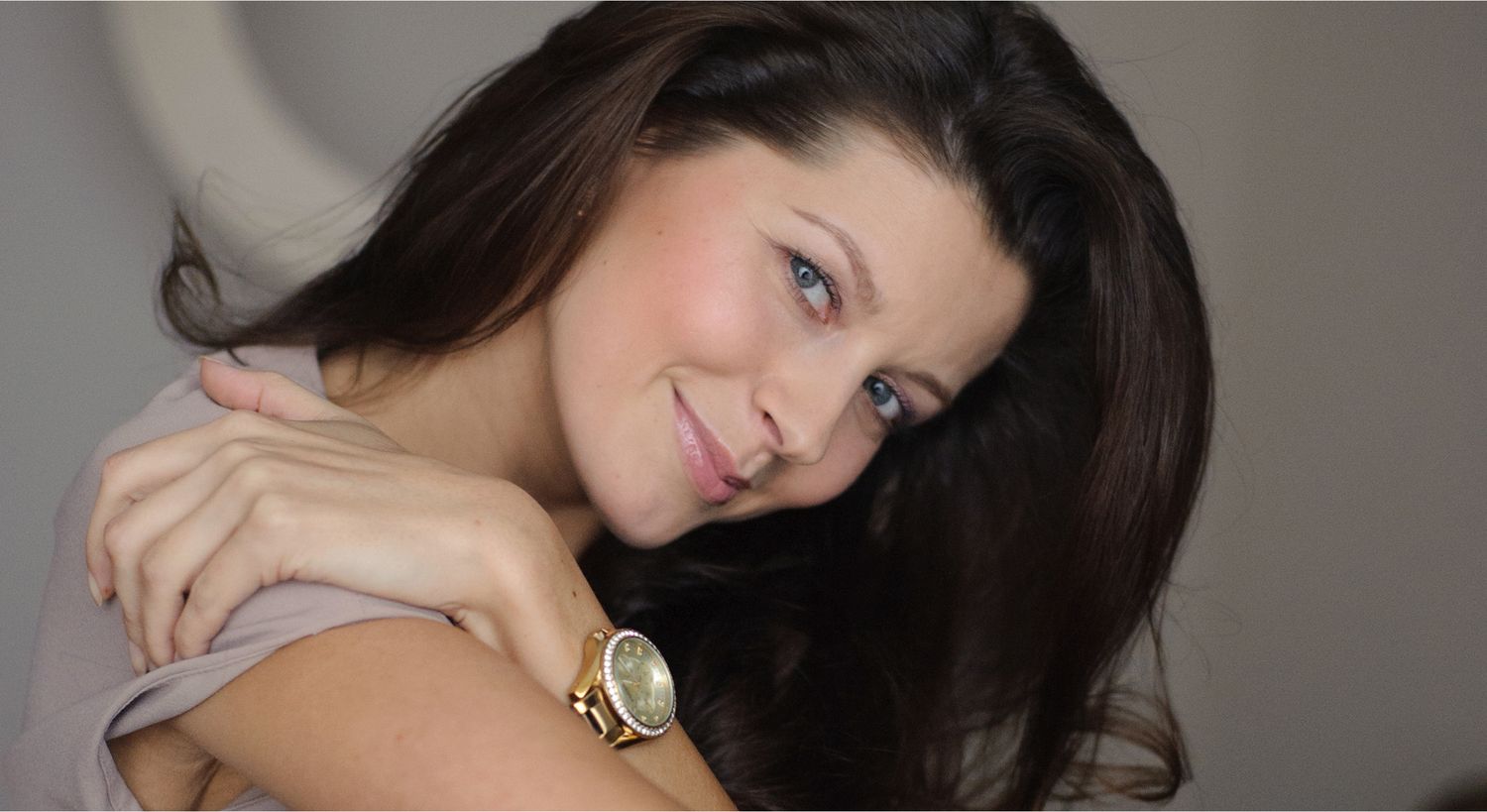 Woman smiling with long hair and watch.