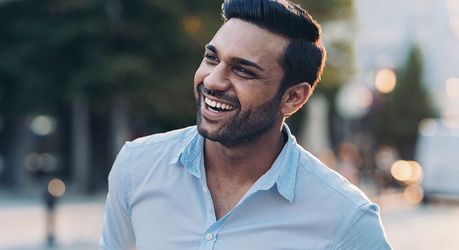 Smiling man in casual shirt outdoors.
