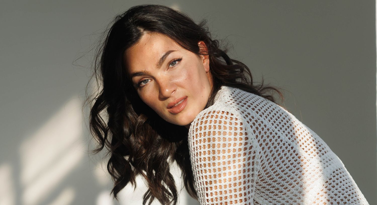 Woman with wavy hair in a white top.