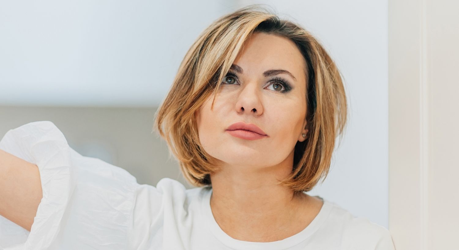 Thoughtful woman with short, styled hair.