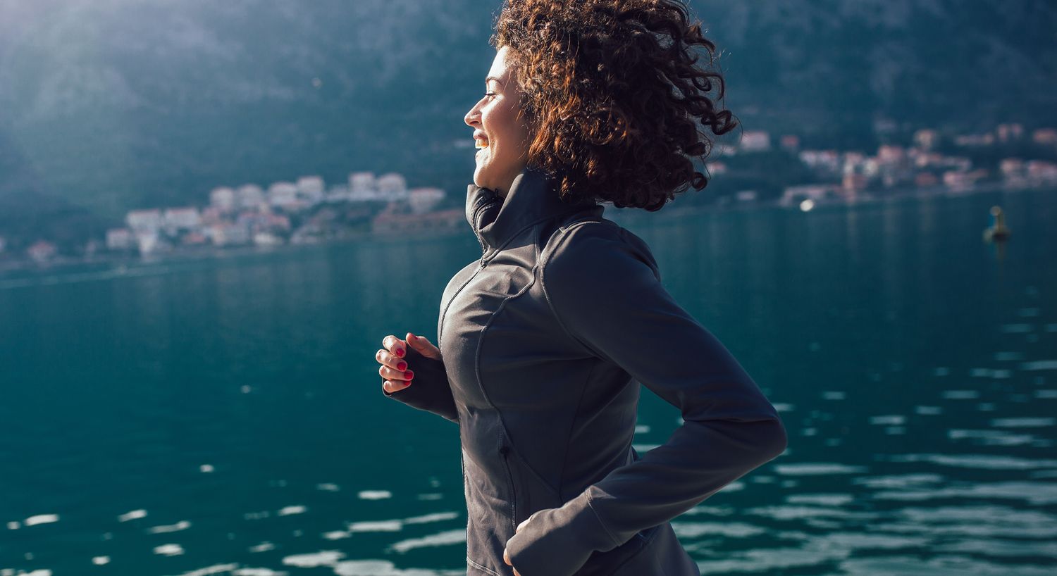 Woman jogging by a serene lake backdrop.