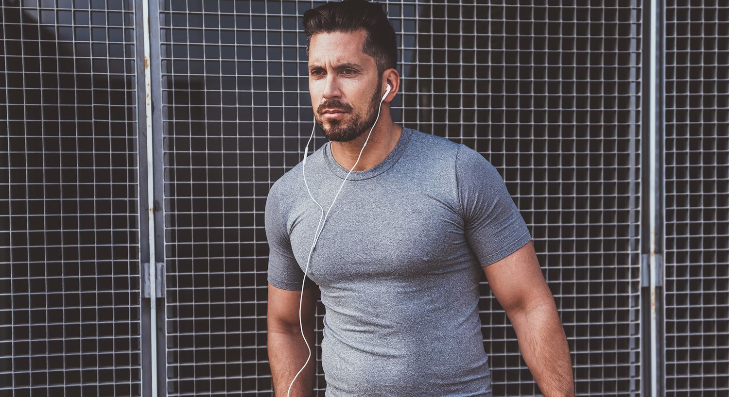 Man listening to music, wearing a gray shirt.